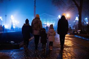 parte posterior de la familia caminando en la ciudad de niebla nocturna. foto