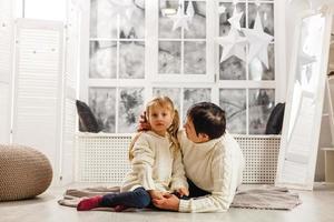 Mother and daughter unwrapping a present lying on the floor in the living room photo