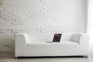 white sofa and laptop against a wall in the apartment photo