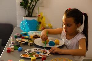 little girl having fun to paint easter eggs photo