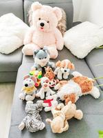 In the room on the couch in a row laid out soft toys of different sizes. Children's soft toys elk, dragon and hare on the background of Wallpaper with a pattern of cracks. photo