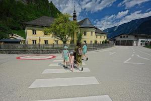 madre cruza un paso de peatones con sus hijos en hallstatt, austria. foto