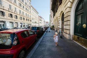 Baby girl with doll at hands walk in Rome street, Italy. photo