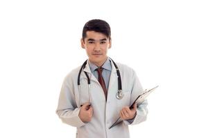 a young doctor in a white lab coat with a stethoscope holding a Tablet and looks into a camera photo