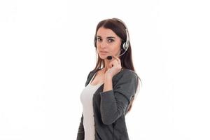 beautiful young girl in headphones and gray jacket looks into the camera and holds hand microphone photo