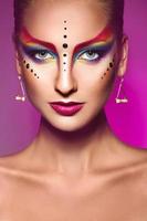 Portrait of fashion model with multicolor make up on purple background photo