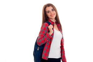 young cute girl in a Plaid Shirt and with a Briefcase on the back looks into the camera and smiling photo