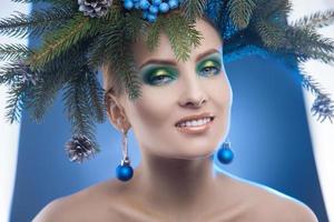 Glamour young woman with nice makeup and christmas tree-wreath on head looking at camera photo