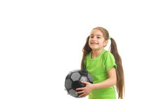 niña sonriente se para en el estudio y sostiene la pelota foto