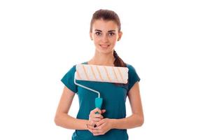 young attractive woman with dark hair in uniforl makes renovations with paint roller in her hands isolated on white background photo