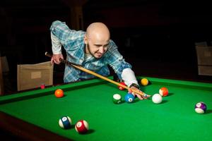 Handsome male model plays at pool billiard table photo