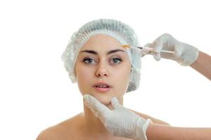 cute young girl without makeup in medical hair Hat looks right and the doctor injects the vaccine on her face a close-up photo