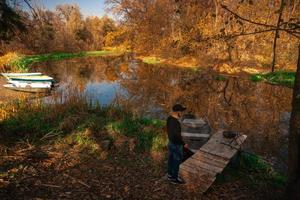handsome guy stands on the river bank in autumn photo