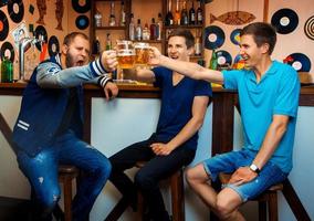 Group of guys drinking beer in a bar and have some fun photo