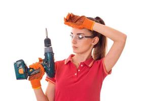 portrait of tired brunette lady builder makes renovation with drill in hands isolated on white background photo