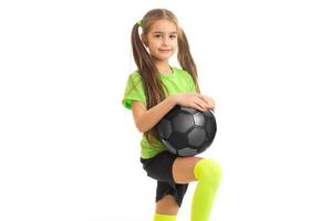 linda niñita con camisa verde con balón de fútbol en las manos foto