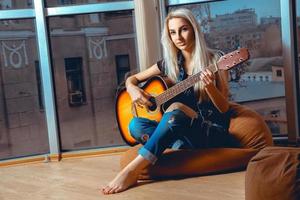 Beauty young blonde lady plays guitar photo