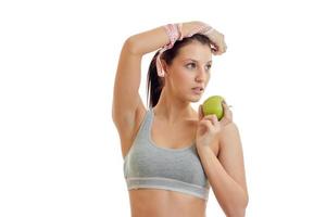 young fitness girl grey top raised her hand up and keeps the Green Apple close-up photo