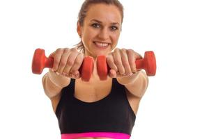 smiling young girl looks arjamo and stretches vpred dumbbells in hands isolated on white background photo