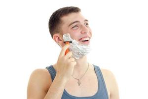 young gay guy with foam on his face looking sideways and shaves photo