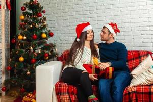 Encantadora pareja feliz en el sofá con regalos de Navidad foto