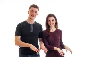 smiling beautiful young couple standing near look right and show hands gestures photo