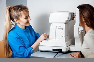a young beautiful ophthalmologist using a non-mydriatic retinal camera on a young girl photo