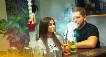 happy couple smokes shisha and drink cocktails photo