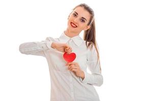 young cheerful woman with red lips preparing to celebrate valentines day with heart symbol in studio isolated on white background photo