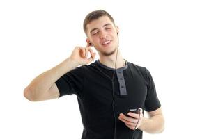 young smiling guy listens to music with headphones with closed eyes photo