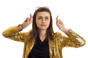 young beautiful girl in shiny jacket, crossed fingers and looks up photo