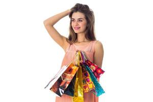 young girl stands sideways keeps hand hair smiling while the other  holds the bright bags isolated on white background photo