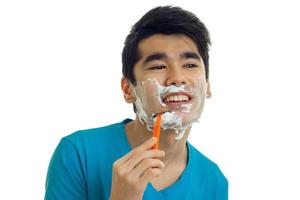 handsome young man with foam on his face shaves his beard and laughs photo