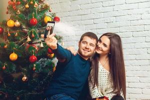 joven pareja amorosa haciendo selfie de navidad foto