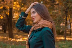girl in a dark shirt and scarf stands sideways in the Park  holds hand hair photo