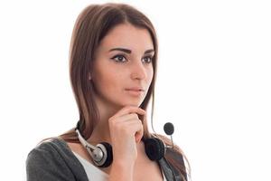 Retrato de una joven y bonita trabajadora del centro de llamadas con auriculares y micrófono mirando hacia otro lado aislada de fondo blanco foto