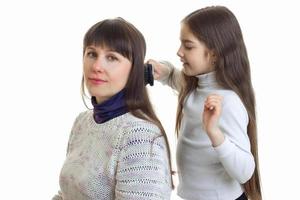 Little girl combs hair to her mother photo