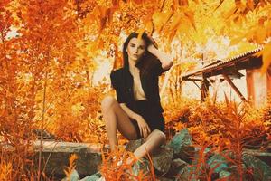 sensual girl in black suit seated on rocks photo