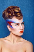 mujer caucásica con maquillaje creativo y peinado sobre fondo azul foto