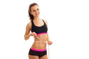 athletic young girl with elastic waist measuring tape measures out belly photo