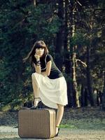 chica de viaje con una maleta en una estación de tren foto
