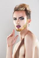 Pretty sensual man with makeup and multicolor beard looking at camera photo