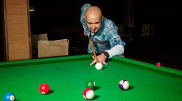 Concentrated man try to hit the cue ball on pool table photo