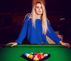 Cute blonde posing near a billiard table with a pyramid of balls photo