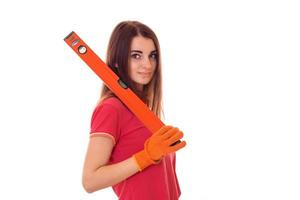 beautiful girl in a red shirt stands sideways and holding a device for measuring the level of isolated on white background photo