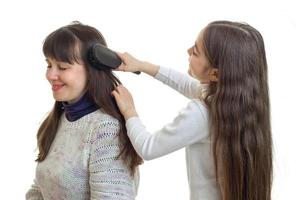 niña peina el pelo de su madre en el estudio foto