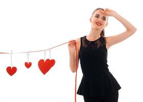 beautiful young girl in black dress holding a Ribbon with cards in the form of hearts photo