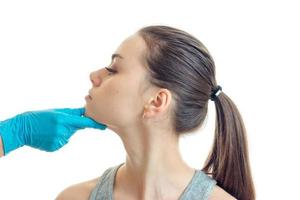 cosmetóloga en un guante azul revisa la cara de una joven de lado de cerca foto
