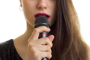 el primer plano de una mujer con labios rojos sostiene un micrófono en la boca
