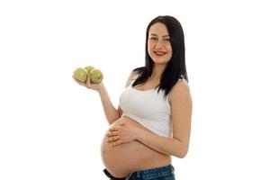 bella joven embarazada con una gran barriga mantiene la manzana en la mano foto